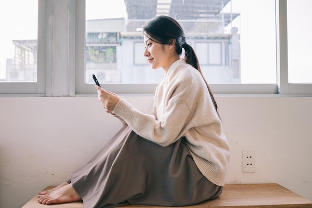 Young Asian woman using smartphone at home