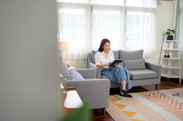 Young asian woman using tablet on sofa in living roomx9