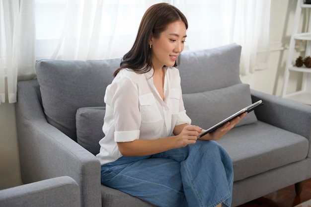 Young asian woman using tablet on sofa in living roomx9