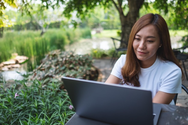 A young asian woman using and working on laptop computer in the park