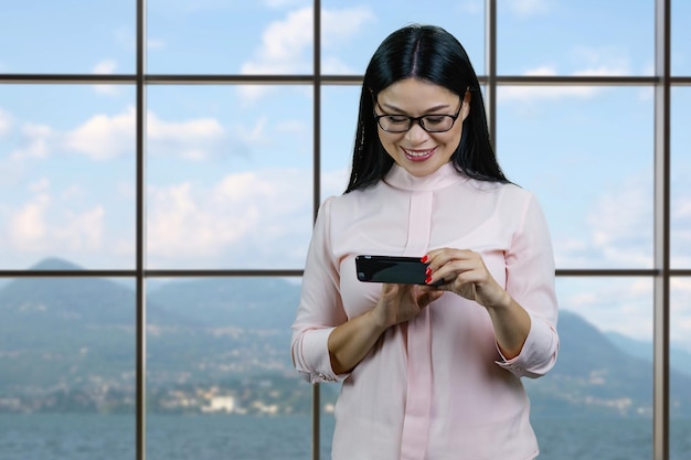 Young asian woman watching a funny video or memes on her smartphone device