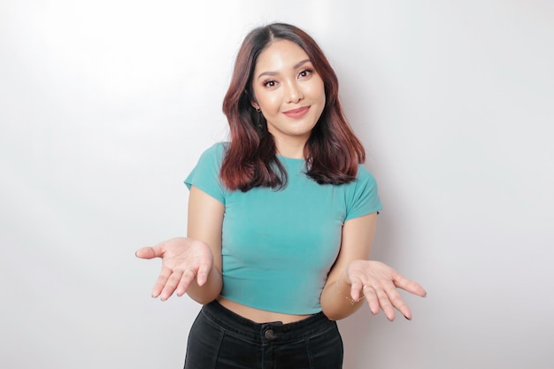 Young Asian woman wearing blue shirt presenting an idea while looking smiling on isolated white background