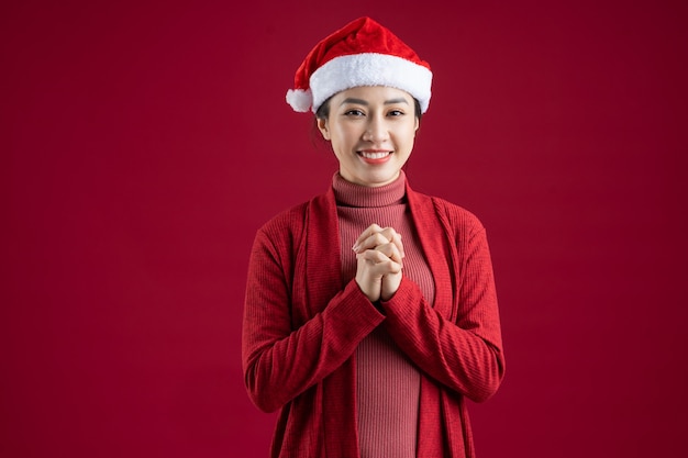 Young Asian woman wearing christmas hat on red background