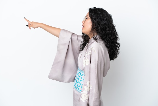 Young asian woman wearing kimono isolated on white background pointing away