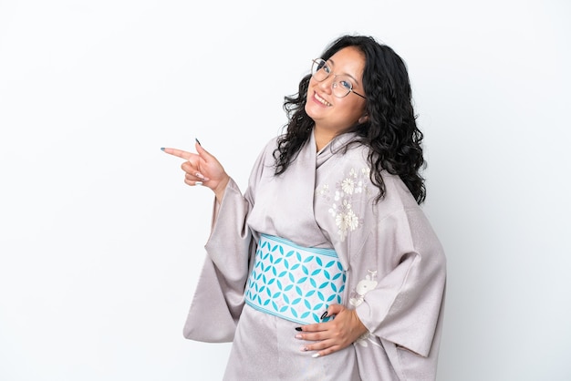 Young asian woman wearing kimono isolated on white background pointing finger to the side and presenting a product