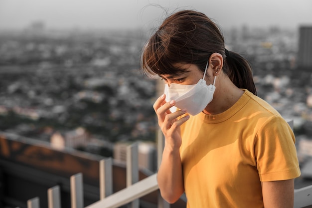 Young Asian woman wearing N95 respiratory mask protect and filter pm25 or particulate matter against bad Air Pollution in City Air Quality Index AQI Unhealthy healthcare concept