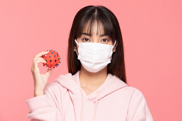 Young asian woman wearing protection mask or surgical mask for protected virus and air pollution making hand stop and hold virus on hand on pink wall,Health care and coronavirus concept