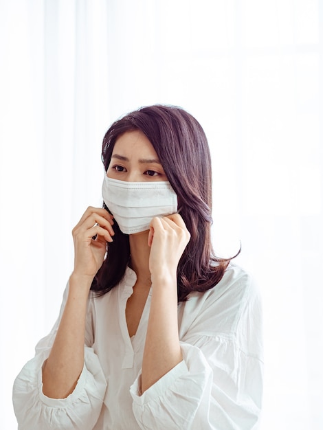 Young asian woman wearing Surgical mask to prevent infection at home quarantine