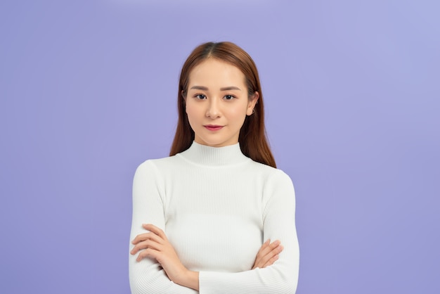 Young asian woman wearing turtleneck sweater standing over isolated white wall happy face smiling with crossed arms. Positive person.