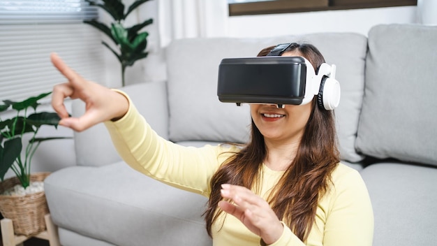 Young Asian woman wearing virtual reality touching air during the VR experience Future technology concept