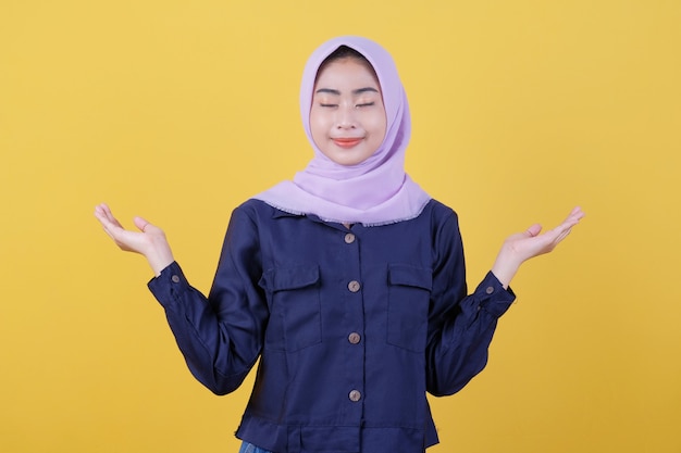 Young Asian woman who is positive with a cheerful smile on the face wearing a hijab and casual clothes in the room is yellow. close her eyes