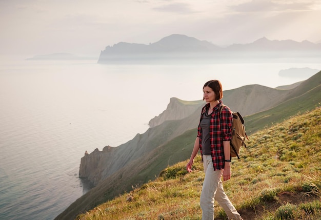 A young Asian woman with a backpack hiking in the summer