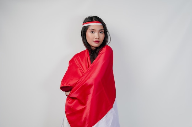 Photo young asian woman with indonesian flag draped over her shoulders and posing for a picture