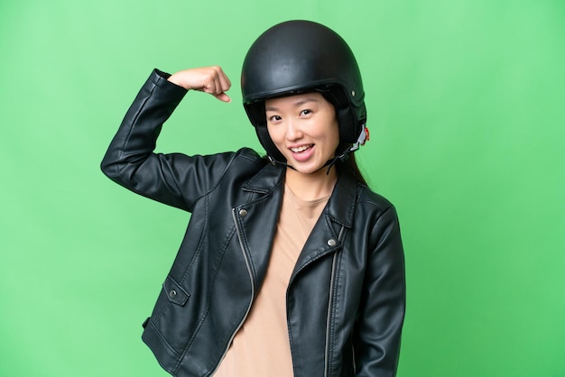 Young Asian woman with a motorcycle helmet over isolated chroma key background doing strong gesture