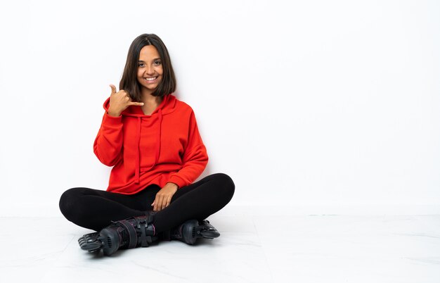 Young asian woman with roller skates on the floor making phone gesture. Call me back sign