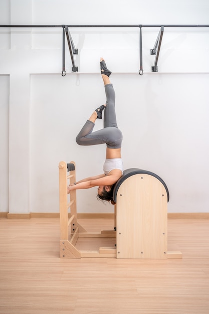 Young Asian woman working on pilates ladder barrel machine during her health exercise training