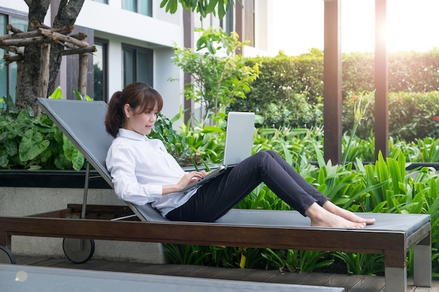 Young asian woman working with laptop and sitting beach chair at hotel