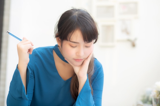 Young asian woman writer thinking and writing on notebook.