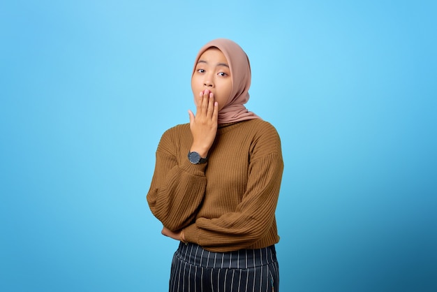 Young Asian woman yawning tired covering mouth with hand on blue background