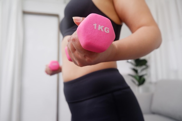 Young Asian women doing exercise at home using dumbbell for exercise arms and upper body