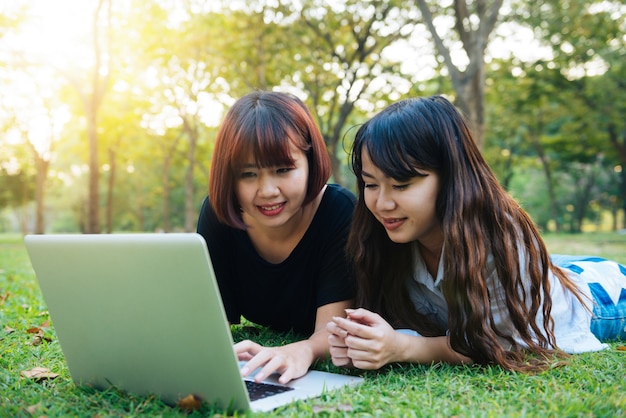 Young asian women legs on the green grass with open laptop