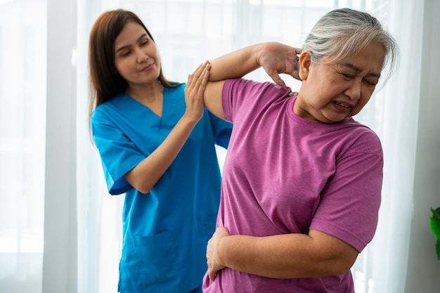 A young Asian women Physiotherapist Nursing is assisting an elderly woman exercise stretching muscles at home or a premium clinic for recovery concept of Physical Therapy