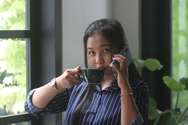 YOUNG ASIAN WOMEN RELAXING READING AND DRINKING COFFEE IN CAFE