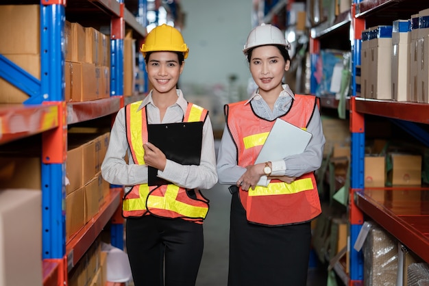 Young Asian women in safety vests standing at warehouse factory