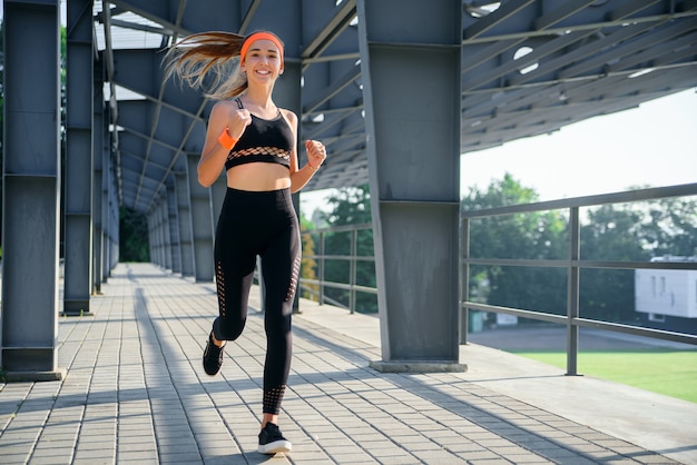 Young athlete is running near the stadium.