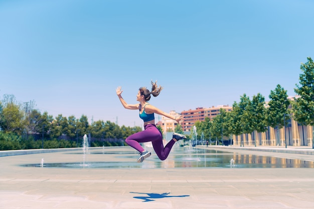 Young athlete jumps with joy she is wearing sportswear she has just finished her training and she is happy freedom concept