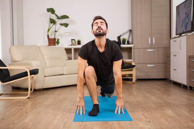 Young athlete man practicing sport in his house in the living room. Healthy lifestyle