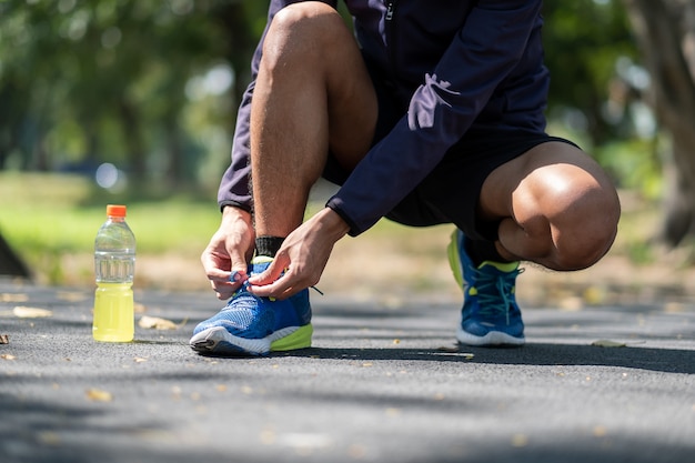 Young athlete man tying running shoes in the park outdoor