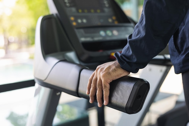 Young athlete running on the treadmill. Close up male runner exercise indoor gym. fitness man jogging wearing sportswear. Workout and healthy