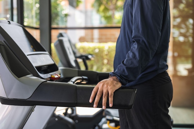 Young athlete running on the treadmill. Close up male runner exercise indoor gym. fitness man jogging wearing sportswear. Workout and healthy