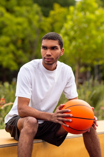 Young athlete sitting with a sad look holding a ball in his hands