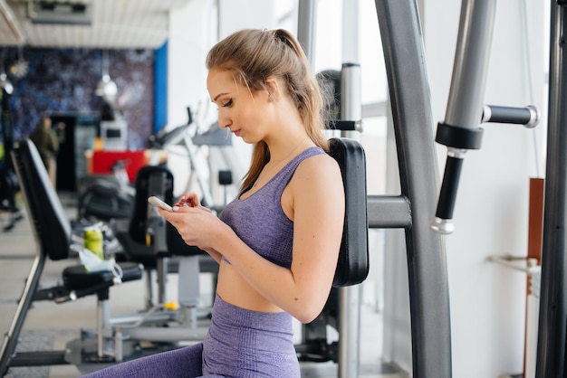 A young athlete uses her phone in the gym and takes a selfie.