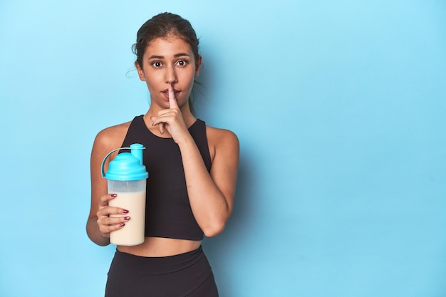 Young athlete with protein shake ready for gym keeping a secret or asking for silence