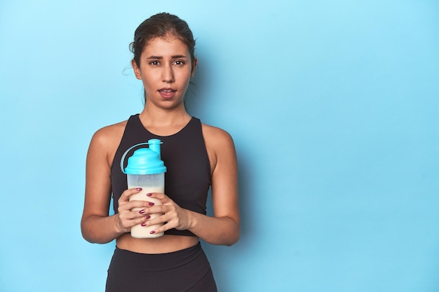 Young athlete with protein shake ready for gym screaming very angry and aggressive