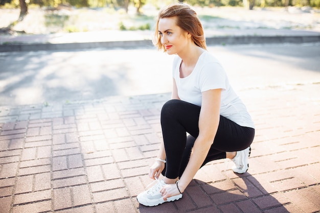 Young athletic girl, tying shoelaces, before Jogging, can be used for advertising, text insertion