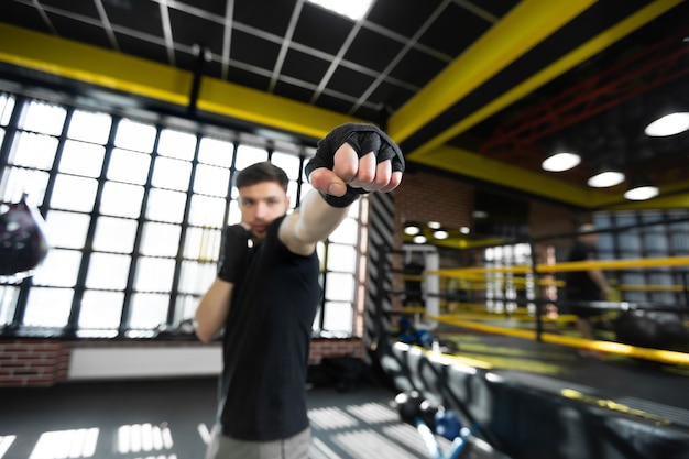 Photo a young athletic male kickboxer clenches his hands into a fist and trains in the ring.