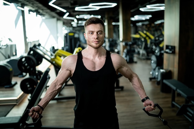 Young athletic man in gym training Handsome bodybuilder working out