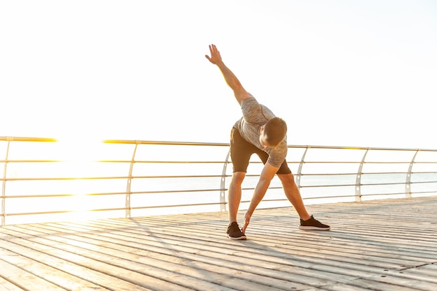 Young athletic man practicing warmup before exercising on beach in the early morning Healthy lifestyle