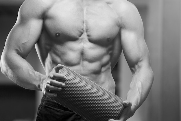 Young athletic man pumping up muscles in the gym at workout Sport and health care concept