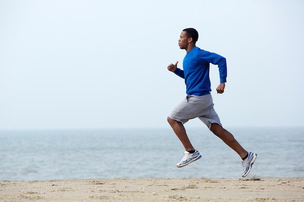 Young athletic man running at the beach