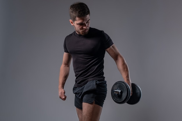 Young athletic man during weight training with dumbbells