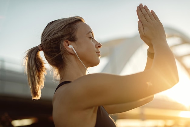 Young athletic woman meditating with eyes closed at sunset