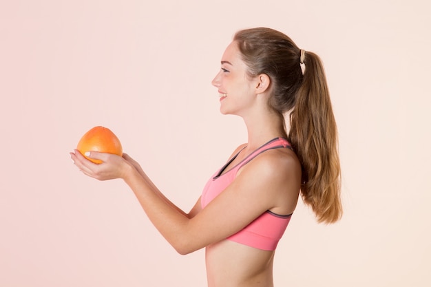 Young athletic woman in profile with a grapefruit in her hands. 