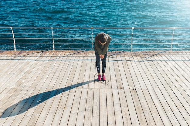 Photo young athletic woman resting after jumping rope on the waterfront on a sunny morning