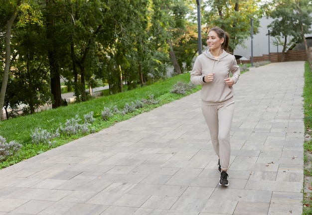 Young athletic woman in sportswear practicing morning jogging outdoors in the park