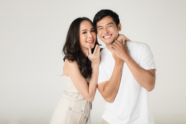 Young attractive Asian couple, man wearing white t shirt and beige pants, woman wearing beige dress. Teasing each other. Concept for pre wedding photography.